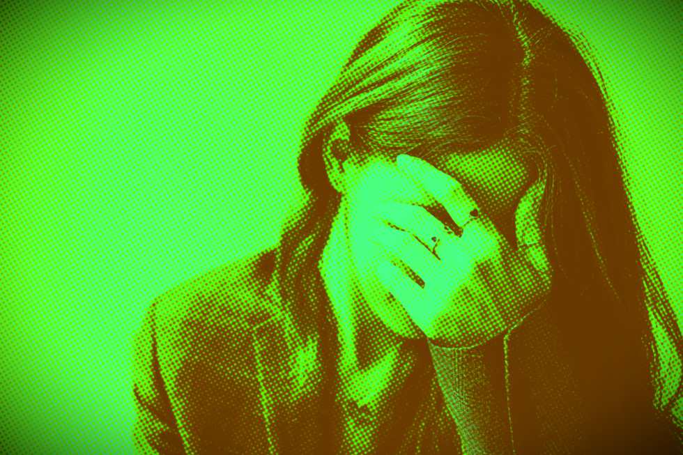 Mulher com o rosto escondido pela mão, aparentando tristeza